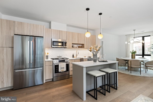 7175 12th St NW Unit 517, Washington, DC 20011 - kitchen with appliances with stainless steel finishes, light brown cabinetry, a kitchen breakfast bar, a center island, and light countertops