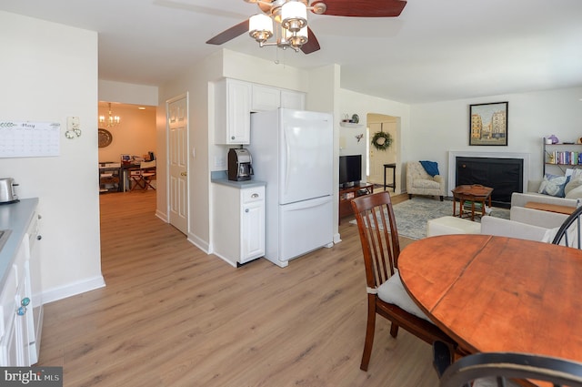 2404 Stokes Rd, Mount Laurel, NJ 08054 - dining area with light wood-type flooring, a ceiling fan, a fireplace, baseboards, and a chandelier