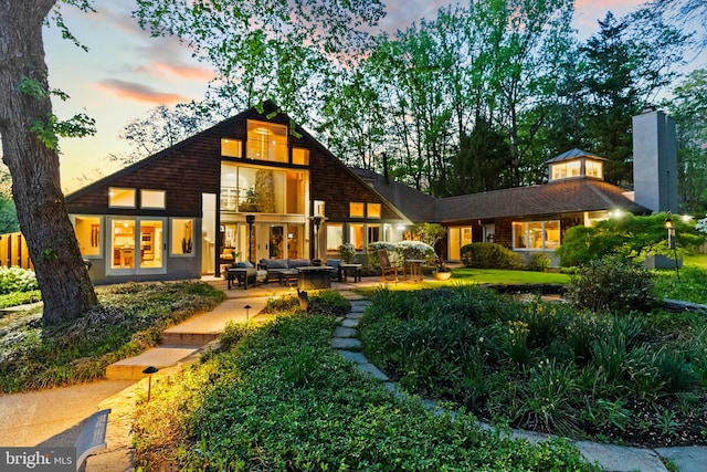 8901 Potomac Station Ln, Potomac, MD 20854 - back of property at dusk with an outdoor living space, a patio, and a chimney