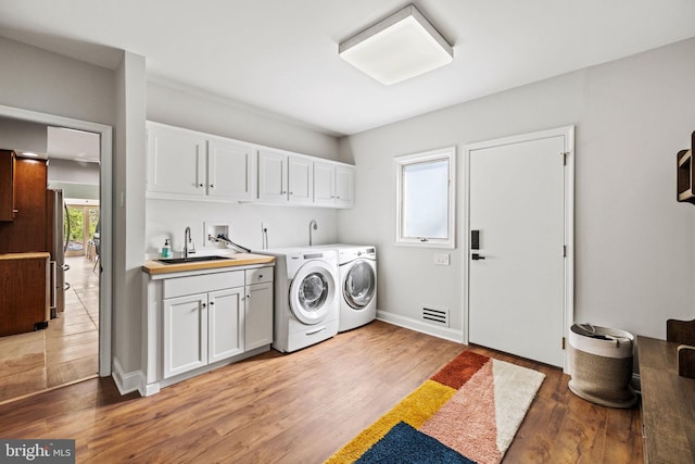 8901 Potomac Station Ln, Potomac, MD 20854 - laundry area featuring cabinet space, washing machine and dryer, light wood finished floors, and baseboards