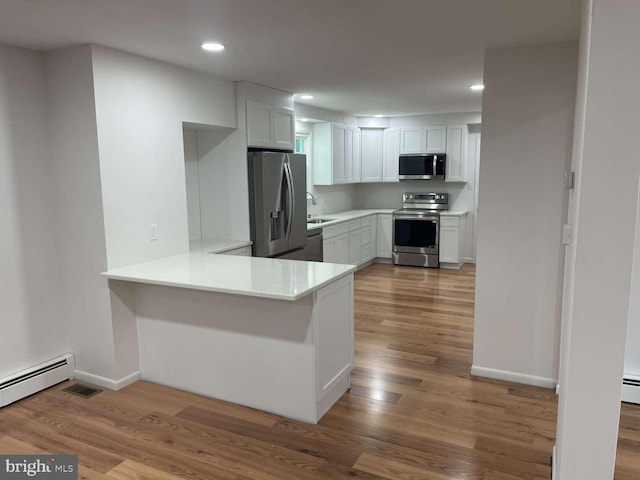 127 Homestead Dr, Doylestown, PA 18901 - kitchen featuring appliances with stainless steel finishes, a baseboard heating unit, light countertops, wood finished floors, and recessed lighting