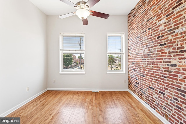 1622 E Clement St, Baltimore, MD 21230 - unfurnished room featuring light wood finished floors, baseboards, a ceiling fan, and brick wall