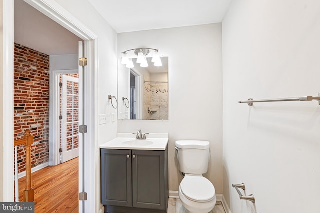 1622 E Clement St, Baltimore, MD 21230 - bathroom featuring toilet, vanity, brick wall, a shower, and baseboards
