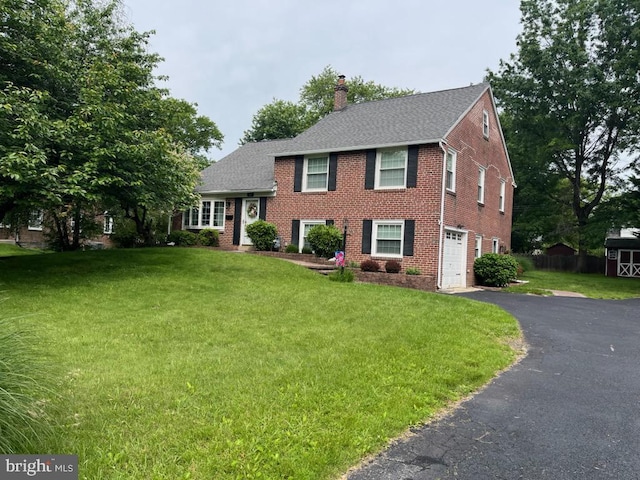 107 Lombardy Dr, Wallingford, PA 19086 - view of front facade with brick siding, an attached garage, asphalt driveway, a chimney, and a front lawn