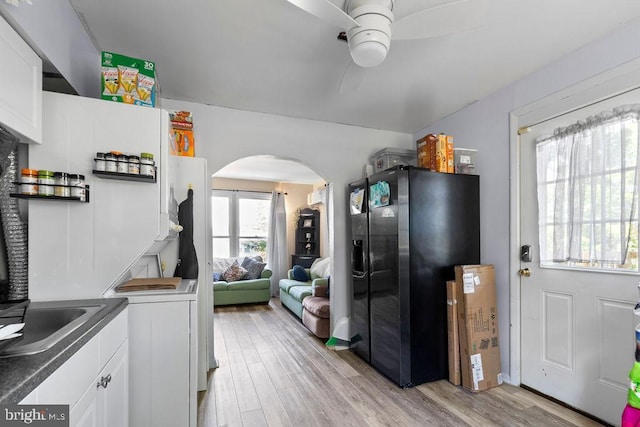 1326 Pine Grove Ave, Baltimore, MD 21237 - kitchen featuring black refrigerator with ice dispenser, arched walkways, ceiling fan, and light wood-style flooring