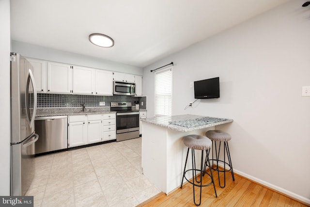 106 Everest Cir Unit 106, West Chester, PA 19382 - kitchen featuring appliances with stainless steel finishes, a sink, white cabinetry, a peninsula, and backsplash