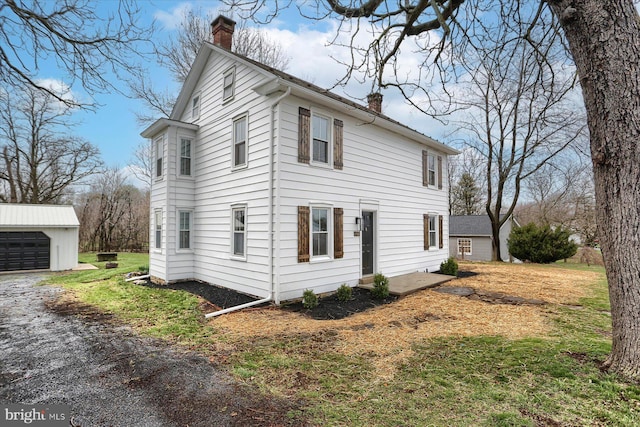 323 Plaza Dr, Palmyra, PA 17078 - view of home's exterior featuring a chimney, an outdoor structure, a garage, and a lawn