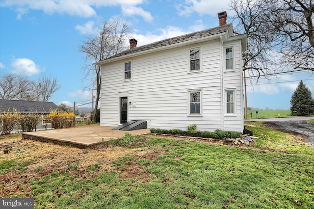 323 Plaza Dr, Palmyra, PA 17078 - back of property featuring a chimney, a yard, and a patio