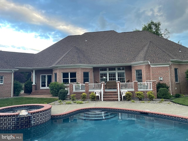 9 Chadwick Dr, Dover, DE 19901 - back of house with brick siding, a shingled roof, and a pool with connected hot tub