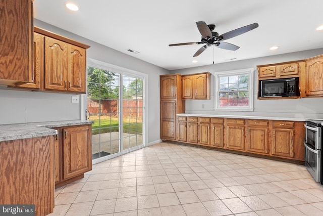95 Twin Oak Dr, Levittown, PA 19056 - kitchen with black microwave, light countertops, range with two ovens, brown cabinetry, and ceiling fan