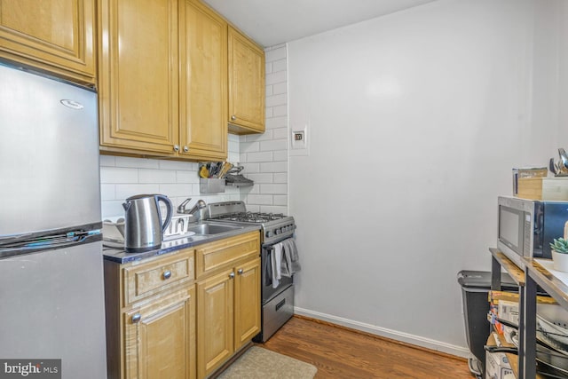 2710 Macomb St NW Unit 202, Washington, DC 20008 - kitchen with appliances with stainless steel finishes, tasteful backsplash, wood finished floors, baseboards, and dark countertops