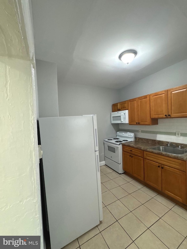4549 N Mole St, Philadelphia, PA 19140 - kitchen with white appliances, a sink, light tile patterned floors, and brown cabinetry