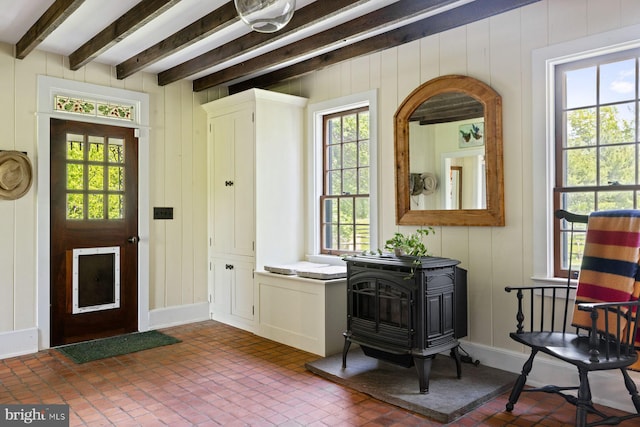 408 Kintner Hill Rd, Upper Black Eddy, PA 18972 - foyer entrance with a wood stove, healthy amount of natural light, beam ceiling, brick patterned floors, and wooden walls