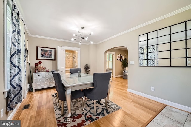 3203 Beverly Rd, Baltimore, MD 21214 - dining space featuring arched walkways, a chandelier, light wood-style flooring, ornamental molding, and baseboards