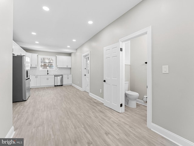 2223 W Indiana Ave, Philadelphia, PA 19132 - kitchen featuring appliances with stainless steel finishes, a sink, white cabinets, backsplash, and light wood-style flooring
