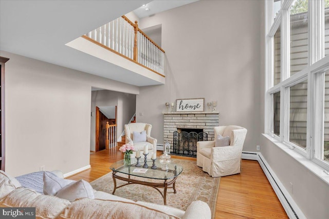 1 Birchall Dr, Haddonfield, NJ 08033 - living area featuring a high ceiling, a baseboard radiator, a stone fireplace, wood finished floors, and baseboards