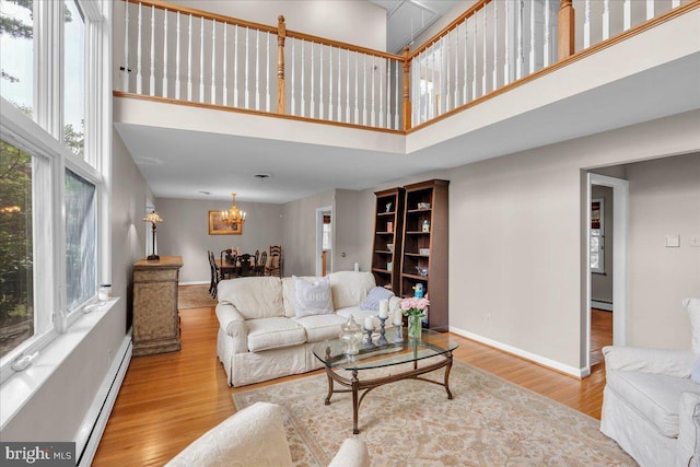 1 Birchall Dr, Haddonfield, NJ 08033 - living room with a towering ceiling, a baseboard heating unit, wood finished floors, a chandelier, and baseboards