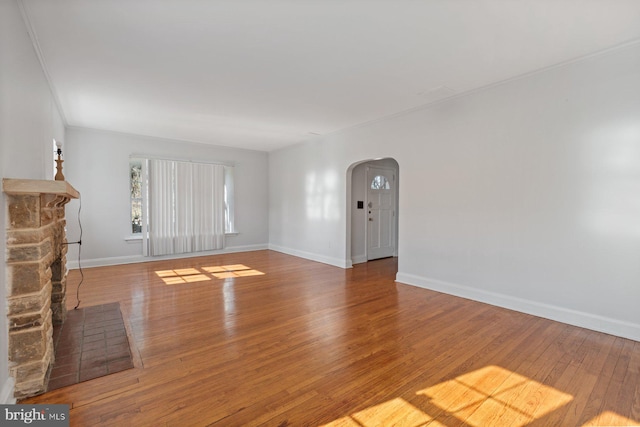 6901 Park Heights Ave, Baltimore, MD 21215 - unfurnished living room featuring arched walkways, wood finished floors, baseboards, and a fireplace