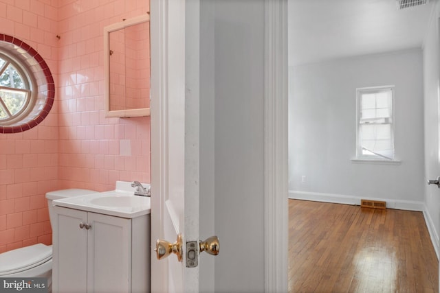 6901 Park Heights Ave, Baltimore, MD 21215 - bathroom featuring plenty of natural light, tile walls, vanity, hardwood / wood-style floors, and toilet