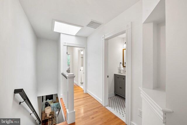 511 S E Ave, Baltimore, MD 21224 - corridor featuring an upstairs landing, light wood finished floors, baseboards, and a skylight