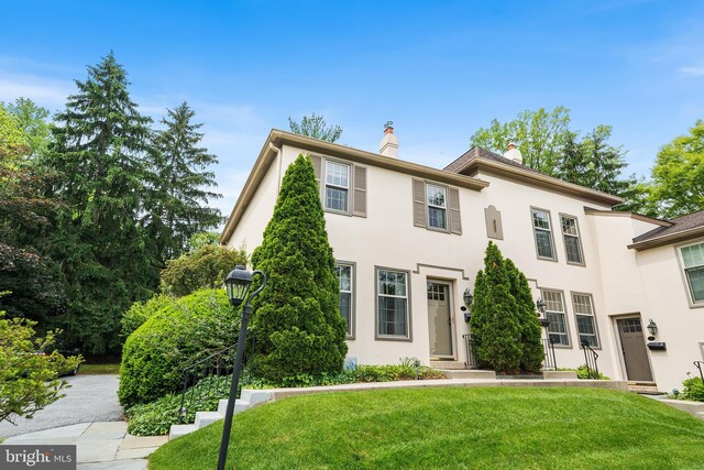 229 Bloomingdale Ave Unit 1, Wayne, PA 19087 - view of front facade featuring stucco siding, a front yard, and a chimney