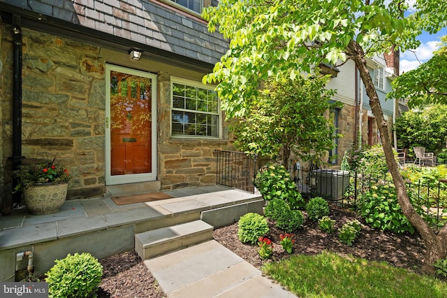 1312 Michigan Ave, Alexandria, VA 22314 - doorway to property featuring stone siding, central AC unit, and mansard roof