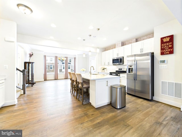 4737 Earl Flanagan Way, Alexandria, VA 22309 - kitchen featuring appliances with stainless steel finishes, a sink, a chandelier, light wood-style floors, and white cabinetry