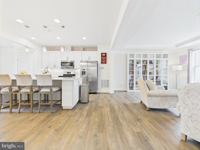 4737 Earl Flanagan Way, Alexandria, VA 22309 - kitchen with stainless steel appliances, white cabinets, light countertops, a kitchen breakfast bar, and light wood-type flooring
