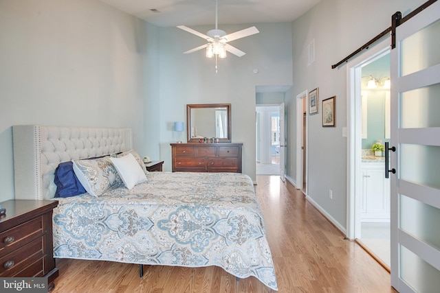 8859 Howland Pl, Bristow, VA 20136 - bedroom featuring high vaulted ceiling, light wood-style flooring, a barn door, and ensuite bath