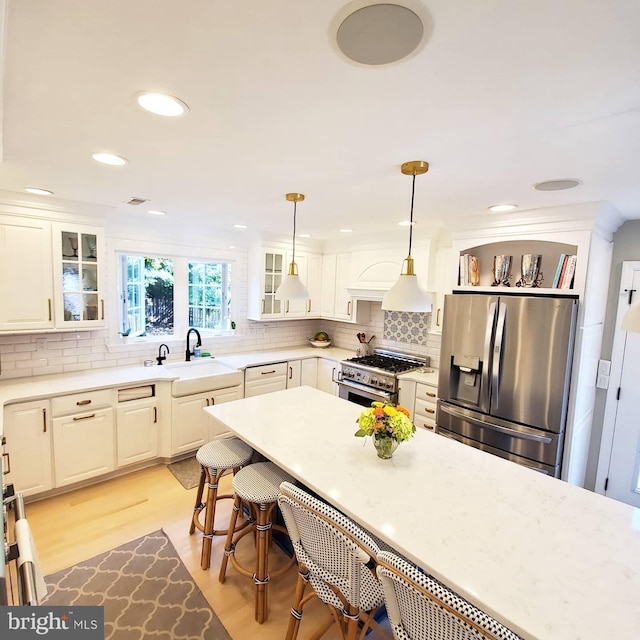 725 Cornerstone Ln, Bryn Mawr, PA 19010 - kitchen with appliances with stainless steel finishes, a sink, a kitchen bar, glass insert cabinets, and backsplash