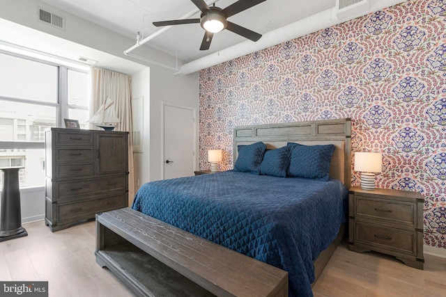 1300 N St NW Unit 817, Washington, DC 20005 - bedroom featuring wallpapered walls, light wood-style floors, baseboards, a ceiling fan, and an accent wall