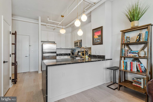 1300 N St NW Unit 817, Washington, DC 20005 - kitchen featuring stainless steel appliances, light wood-type flooring, a peninsula, and white cabinetry