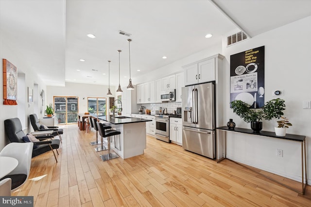810 S 49th St, Philadelphia, PA 19143 - kitchen with high end appliances, dark countertops, a breakfast bar area, light wood finished floors, and recessed lighting