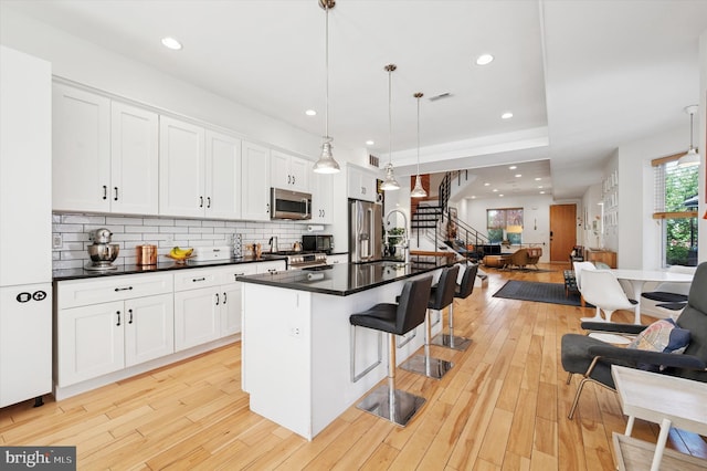 810 S 49th St, Philadelphia, PA 19143 - kitchen with appliances with stainless steel finishes, open floor plan, dark countertops, a breakfast bar area, and white cabinetry