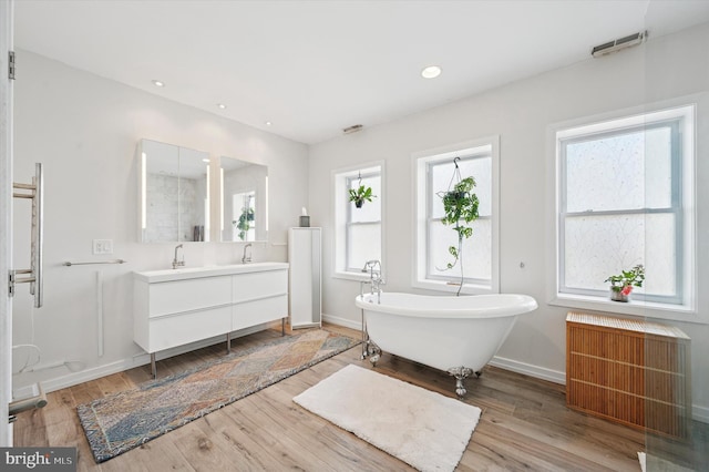 810 S 49th St, Philadelphia, PA 19143 - bathroom featuring radiator, a freestanding bath, double vanity, wood finished floors, and recessed lighting