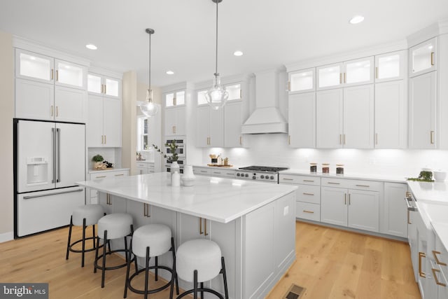 1749 Beulah Rd, Vienna, VA 22182 - kitchen with high end white fridge, custom range hood, a center island, light wood finished floors, and white cabinetry
