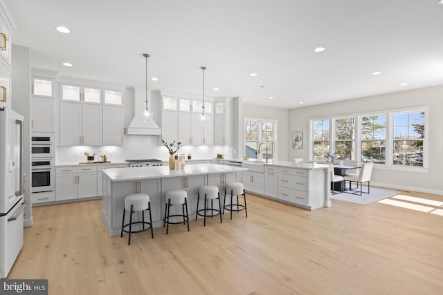 1749 Beulah Rd, Vienna, VA 22182 - kitchen with custom exhaust hood, a kitchen island, light wood-style floors, a kitchen bar, and a peninsula
