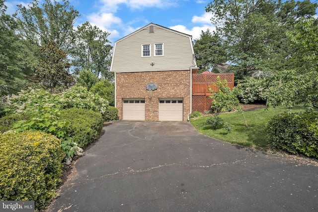 3930 6th St S, Arlington, VA 22204 - view of side of home with a gambrel roof, asphalt driveway, brick siding, a garage, and a deck