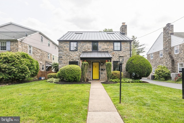 137 Sutton Rd, Ardmore, PA 19003 - tudor home with a standing seam roof, stone siding, a front lawn, a chimney, and metal roof