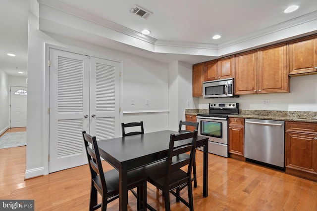 408 Kennedy St NW Unit 202, Washington, DC 20011 - kitchen featuring stainless steel appliances, light wood finished floors, ornamental molding, brown cabinetry, and stone countertops