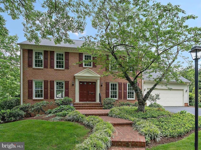 9728 Whetstone Dr, Montgomery Village, MD 20886 - colonial-style house featuring driveway, an attached garage, brick siding, and a front yard