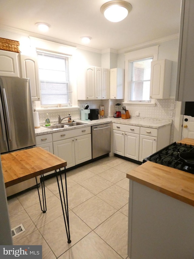 503 Division St, Harrisburg, PA 17110 - kitchen featuring dishwasher, a sink, ornamental molding, backsplash, and white cabinetry