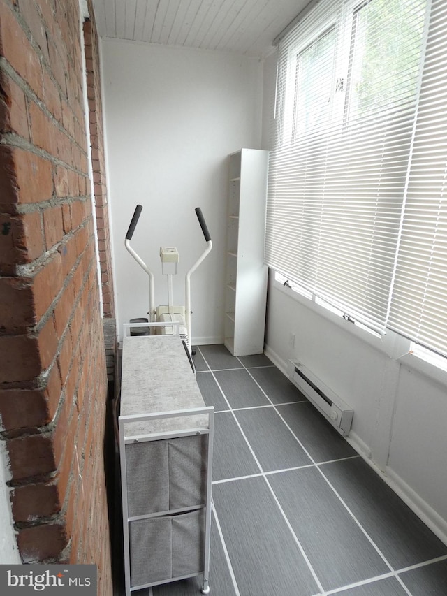 503 Division St, Harrisburg, PA 17110 - interior space with baseboard heating, brick wall, dark tile patterned floors, and baseboards