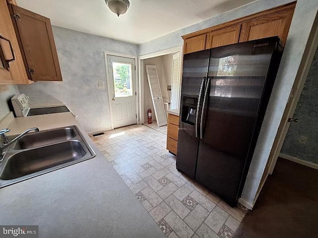 226 Bethel Rd, Somers Point, NJ 08244 - kitchen with black fridge with ice dispenser, range, a sink, light countertops, and brown cabinetry