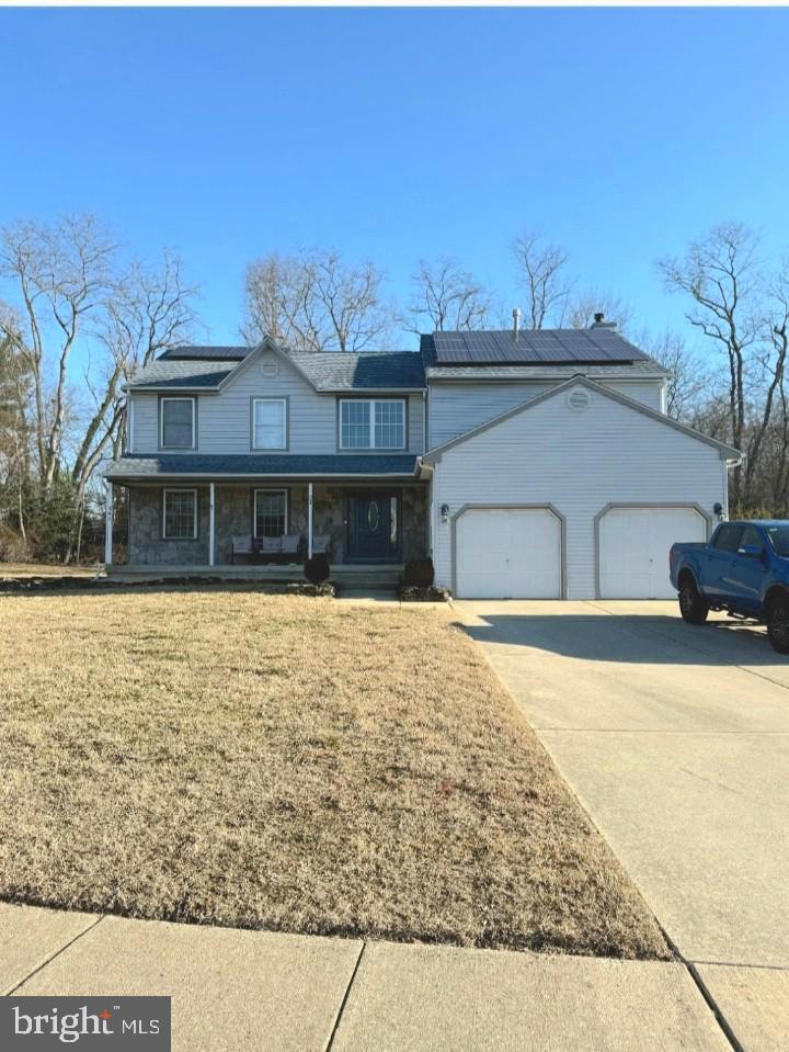31 Meadow Ln, Eastampton, NJ 08060 - view of front of property featuring an attached garage, solar panels, driveway, a porch, and a front yard