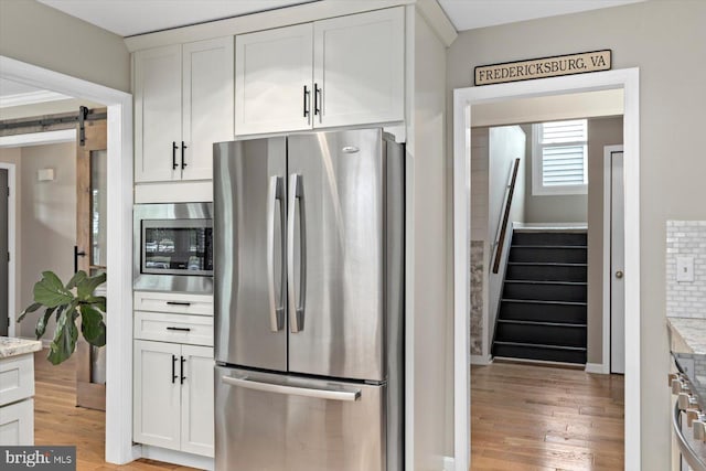 9 Tally Ho Dr, Fredericksburg, VA 22405 - kitchen with stainless steel appliances, a barn door, light stone counters, and white cabinetry
