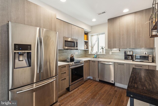 912 N 16th St Unit C, Philadelphia, PA 19130 - kitchen featuring appliances with stainless steel finishes, modern cabinets, light countertops, dark wood-style floors, and decorative backsplash