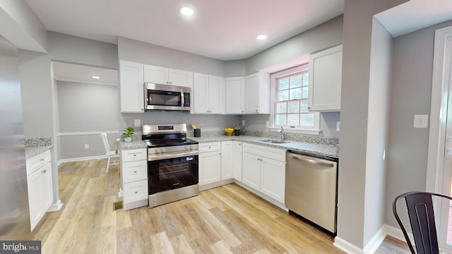 1202 Eugenia Way, Bel Air, MD 21014 - kitchen featuring appliances with stainless steel finishes, white cabinets, light stone counters, light wood-type flooring, and a sink