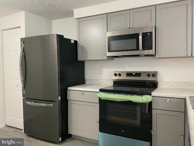 508 Boysenberry Ln, Frederick, MD 21703 - kitchen featuring stainless steel appliances, gray cabinetry, light countertops, a textured ceiling, and light wood-type flooring