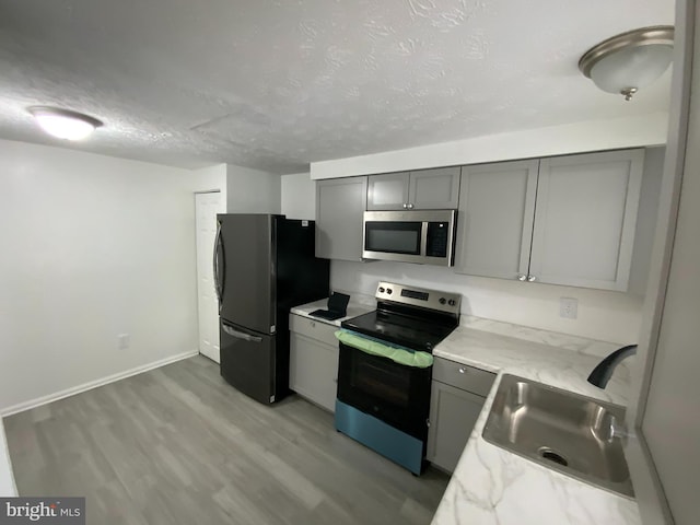 508 Boysenberry Ln, Frederick, MD 21703 - kitchen featuring appliances with stainless steel finishes, gray cabinets, a sink, a textured ceiling, and light wood-style floors
